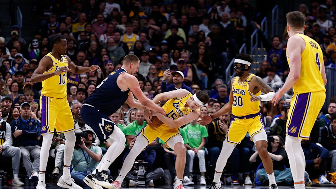 Mar 14, 2025; Denver, Colorado, USA; Los Angeles Lakers guard Austin Reaves (15) steals the ball away from Denver Nuggets center Nikola Jokic (15) as center Christian Koloko (10) and guard Jordan Goodwin (30) defend in the fourth quarter at Ball Arena. Mandatory Credit: Isaiah J. Downing-Imagn Images