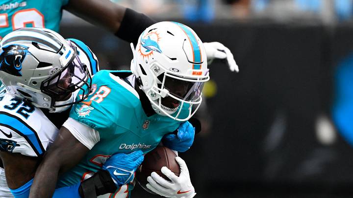Miami Dolphins running back De'Von Achane (28) runs as Carolina Panthers linebacker Trevin Wallace (32) defends in the first quarter at Bank of America Stadium.