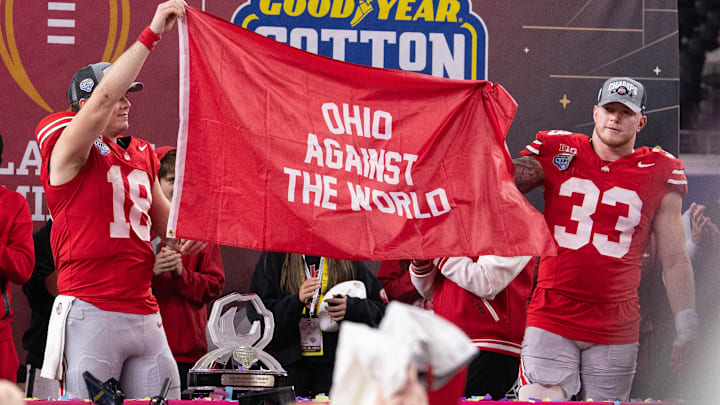 Ohio State quarterback Will Howard and defensive end Jack Sawyer hold up a banner after earning a spot in the College Football Playoff national championship game.