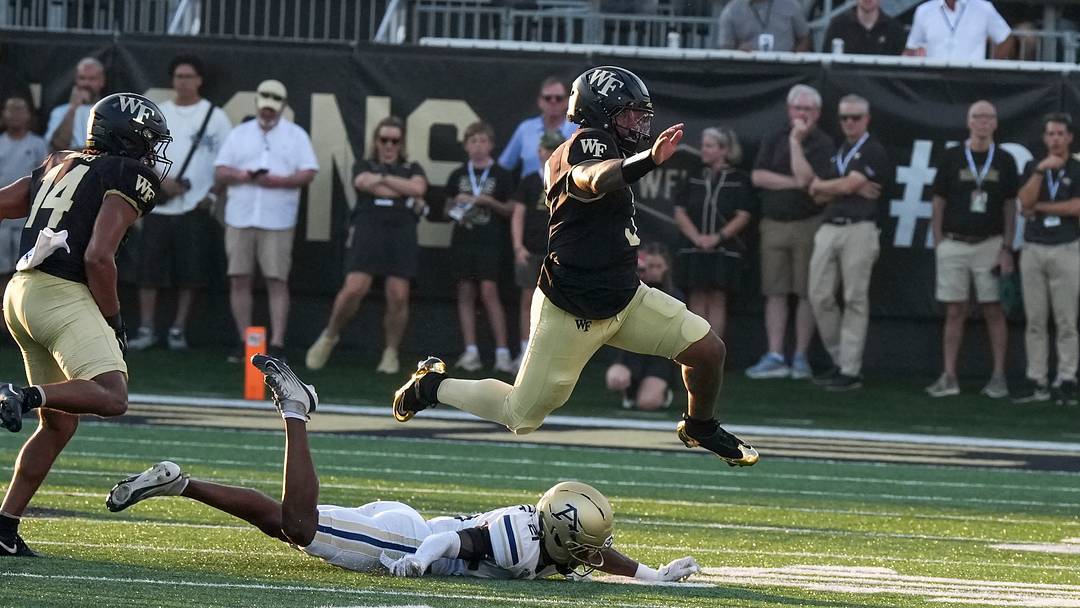 Sep 3, 2026; Winston-Salem, North Carolina, USA;  Wake Forest Demon Deacons quarterback Gio Lopez (3) leaps over Akron Zips defensive back Catrell White (21) during the first half at Allegacy Federal Credit Union Stadium.  Mandatory Credit: Jim Dedmon-Imagn Images