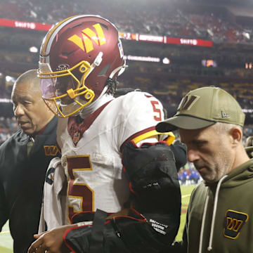 Washington Commanders quarterback Jayden Daniels is helped off the field after an injury.