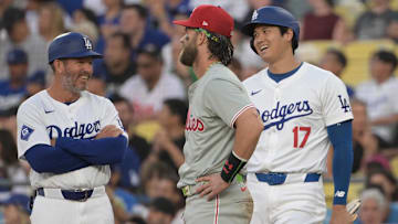 Aug 7, 2024; Los Angeles, California, USA;  Los Angeles Dodgers first base coach Clayton McCullough (86), designated hitter Shohei Ohtani (17) and Philadelphia Phillies first baseman Bryce Harper (3) laugh as they wait for a replay in the first inning at Dodger Stadium. 
