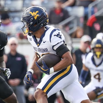 Nov 1, 2025; Houston, Texas, USA; West Virginia Mountaineers running back Diore Hubbard (20) rushes against Houston Cougars defensive end Latreveon McCutchin (10) in the first half at TDECU Stadium.
