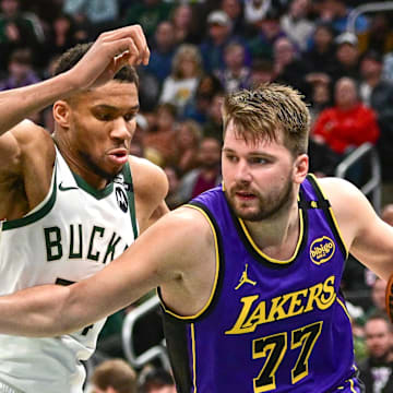 Mar 13, 2025; Milwaukee, Wisconsin, USA;  Los Angeles Lakers guard Luka Doncic (77) drives to the basket against Milwaukee Bucks forward Giannis Antetokounmpo (34) in the third quarter at Fiserv Forum. Mandatory Credit: Benny Sieu-Imagn Images