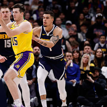 Apr 29, 2024; Denver, Colorado, USA; Los Angeles Lakers guard Austin Reaves (15) passes the ball as Denver Nuggets center Nikola Jokic (15) and forward Michael Porter Jr. (1) defend in the third quarter during game five of the first round for the 2024 NBA playoffs at Ball Arena. Mandatory Credit: Isaiah J. Downing-Imagn Images