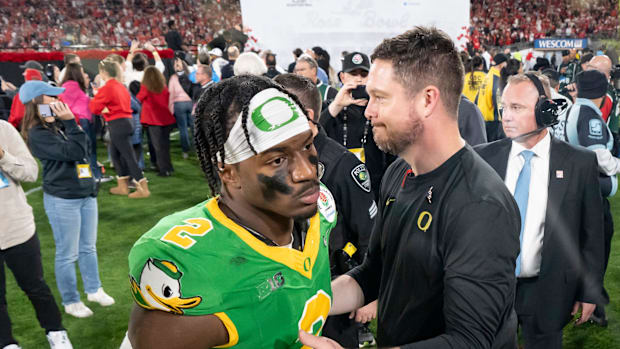 Oregon head coach Dan Lanning, right greets inside linebacker Jeffrey Bassa as the team walks off the field