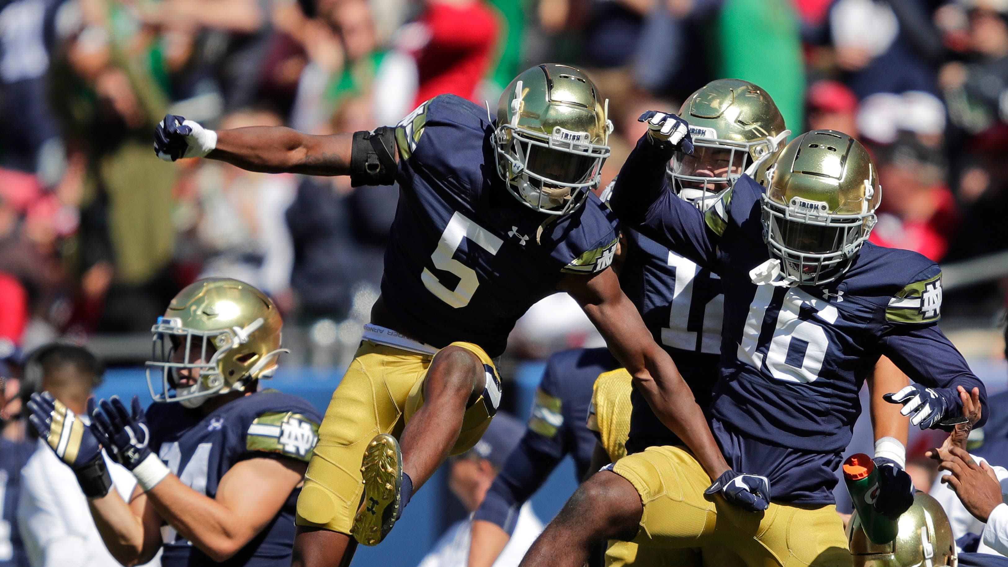 Notre Dame Fighting Irish cornerback Cam Hart celebrates with teammates by leaping into the air.