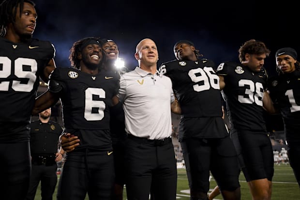 Vanderbilt coach Clark Lea stands with locked arms with his team during a game.