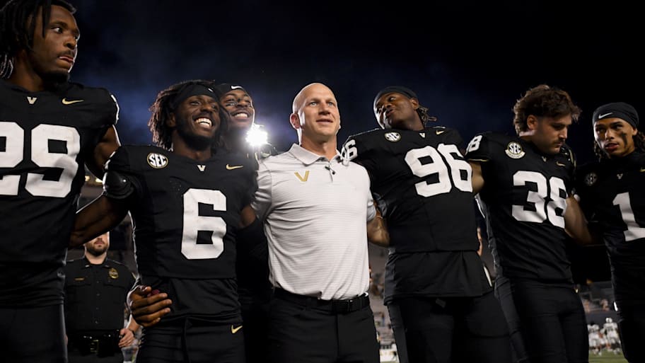 Vanderbilt coach Clark Lea stands with locked arms with his team during a game.