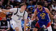Dec 1, 2025; Denver, Colorado, USA; Dallas Mavericks forward Cooper Flagg (32) controls the ball as Denver Nuggets guard Jamal Murray (27) guards in the second quarter at Ball Arena.