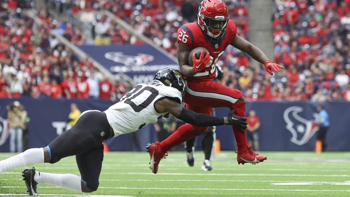 Nov 26, 2023; Houston, Texas, USA; Houston Texans running back Devin Singletary (26) runs with the ball as Jacksonville Jaguars cornerback Montaric Brown (30) attempts to make a tackle during the third quarter at NRG Stadium. Mandatory Credit: Troy Taormina-USA TODAY Sports