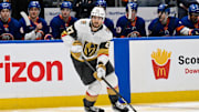 Feb 4, 2025; Elmont, New York, USA;  Vegas Golden Knights defenseman Shea Theodore (27) skates with the puck against the New York Islanders during the third period at UBS Arena. Mandatory Credit: Dennis Schneidler-Imagn Images