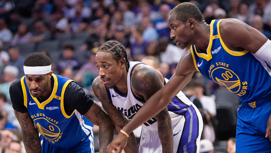 Oct 9, 2024; Sacramento, California, USA; Golden State Warriors guard Gary Payton II (0) and forward Jonathan Kuminga (00) defend against Sacramento Kings forward DeMar DeRozan (10) during a free throw attempt in the second quarter at Golden 1 Center. Mandatory Credit: Ed Szczepanski-Imagn Images
