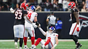 Dec 22, 2024; Atlanta, Georgia, USA; New York Giants quarterback Drew Lock (2) is helped up by guard Greg Van Roten (74) after an interception for a touchdown against the Atlanta Falcons in the second quarter at Mercedes-Benz Stadium. Mandatory Credit: Brett Davis-Imagn Images