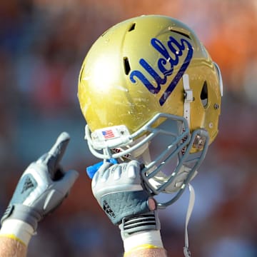 Sept 25, 2010; Austin, TX, USA; A member of the UCLA Bruins holds up his helmet to acknowledge their fans against the Texas Longhorns during the fourth quarter at Texas Memorial Stadium. UCLA beat Texas 34-12. Mandatory Credit: Brendan Maloney-Imagn Images