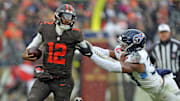 Cleveland Browns quarterback Shedeur Sanders (12) picks up a first down on his feet ahead of Tennessee Titans linebacker Cedric Gray (33) during the first half of an NFL football game at Huntington Bank Field, Dec. 7, 2025, in Cleveland, Ohio.