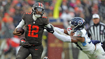 Cleveland Browns quarterback Shedeur Sanders (12) picks up a first down on his feet ahead of Tennessee Titans linebacker Cedric Gray (33) during the first half of an NFL football game at Huntington Bank Field, Dec. 7, 2025, in Cleveland, Ohio.