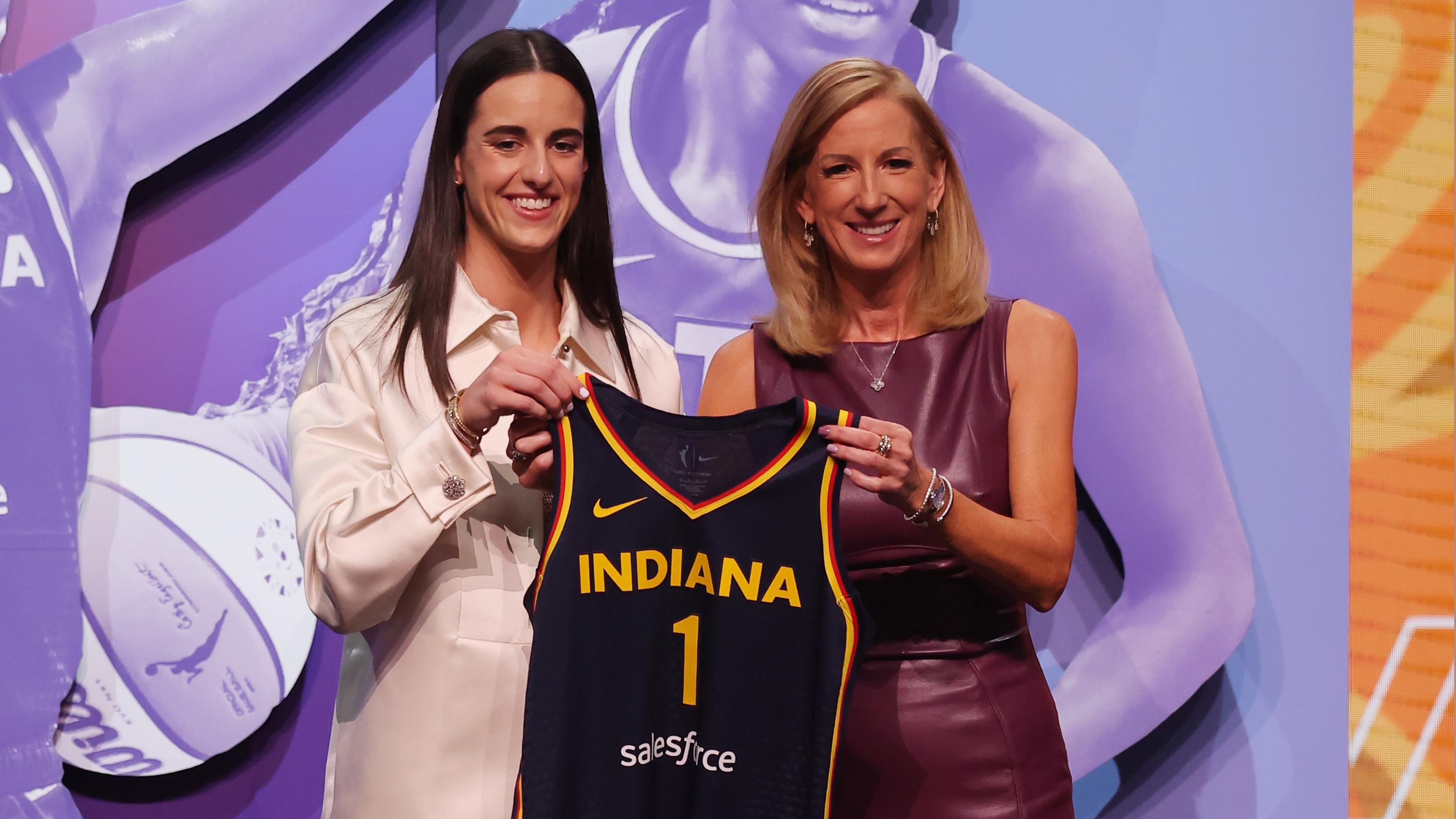 Caitlin Clark holding the No. 1 Indiana Fever on WNBA Draft night. 