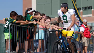 Green Bay Packers wide receiver Christian Watson (9) greets fans while riding a fan's bicycle along the DreamDrive before the start of training camp on Aug. 3, 2023, in Green Bay, Wis.