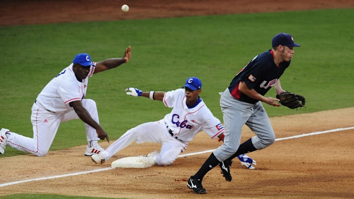 Hector Olivera of Cuba triples during the 2008 Olympics while Mike Hessman of the United States bungles a throw.