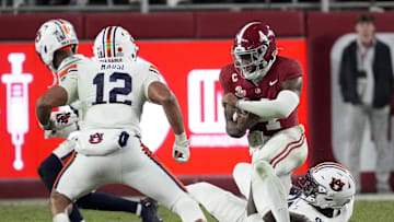 Nov 30, 2024; Tuscaloosa, Alabama, USA;  Alabama Crimson Tide quarterback Jalen Milroe (4) cuts back against Auburn Tigers linebacker Dorian Mausi (12) during the second half at Bryant-Denny Stadium. Alabama won 28-14. Mandatory Credit: Gary Cosby Jr.-Imagn Images