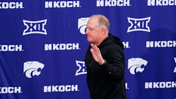 Kansas State football head coach Chris Klieman waves his hand after standing up at a press announcement where he shared his thoughts on his retirement.