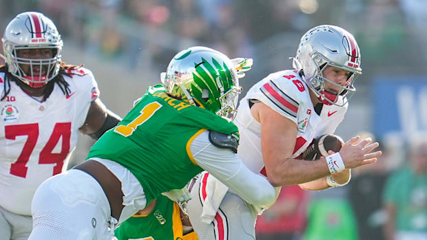 Ohio State Buckeyes quarterback Will Howard (18) runs through Oregon Ducks defensive end Jordan Burch (1)