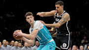 Dec 1, 2025; Brooklyn, New York, USA; Charlotte Hornets center Ryan Kalkbrenner (11) looks to pass the ball against Brooklyn Nets forward Michael Porter Jr. (17) and center Nic Claxton (33) during the first quarter at Barclays Center. Mandatory Credit: Brad Penner-Imagn Images