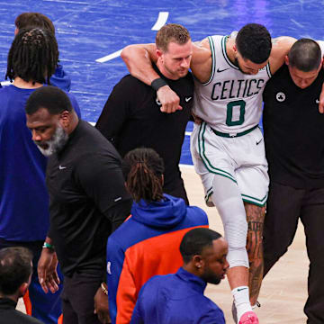 May 12, 2025; New York, New York, USA: Boston Celtics forward Jayson Tatum (0) is helped off the court by after an injury in the second half during game four of the second round for the 2025 NBA Playoffs against the New York Knicks at Madison Square Garden. Tatum would leave the game with an injury after this play. Mandatory Credit: Vincent Carchietta-Imagn Images