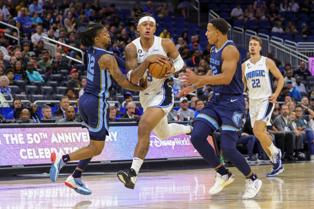 Orlando Magic forward Paolo Banchero brings the ball upcourt against Memphis Grizzlies guard Ja Morant and guard Desmond Bane