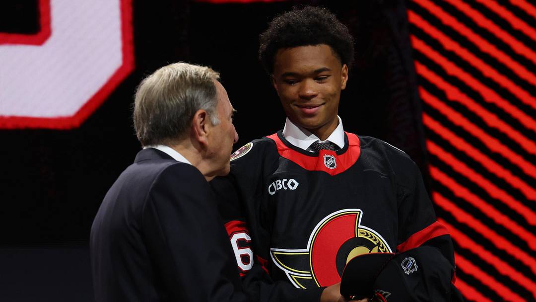 Jun 26, 2026; Buffalo, New York, USA; Jaxson Cover reacts beside NHL commissioner Gary Bettman after being selected with the thirty second pick in the first round of the 2026 NHL Draft by the Ottawa Senators at KeyBank Center. Mandatory Credit: Timothy T. Ludwig-Imagn Images