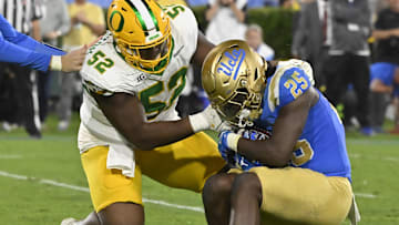Sep 28, 2024; Pasadena, California, USA; Oregon Ducks defensive lineman A'Mauri Washington (52) tackles UCLA Bruins running back T.J. Harden (25) in the backfield during the third quarter at Rose Bowl. Mandatory Credit: Robert Hanashiro-Imagn Images