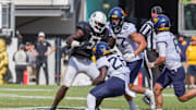 Oct 28, 2023; Orlando, Florida, USA; West Virginia Mountaineers running back Justin Johnson Jr. (26) is tackled by UCF Knights defensive end Malachi Lawrence (51) during the second half at FBC Mortgage Stadium. Mandatory Credit: Mike Watters-Imagn Images