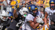Oct 28, 2023; Orlando, Florida, USA; West Virginia Mountaineers running back CJ Donaldson Jr. (4) carries the ball as UCF Knights defensive back Nikai Martinez (21) move in for the tackle during the second half at FBC Mortgage Stadium. Mike Watters-USA TODAY Sports