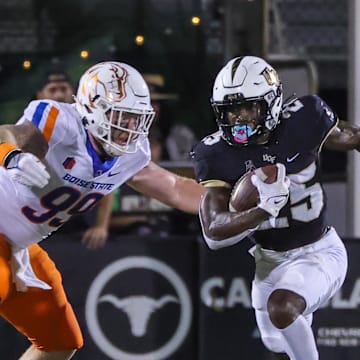 Sep 2, 2021; Orlando, Florida, USA; UCF Knights running back Johnny Richardson (25) runs the ball as Boise State Broncos defensive tackle Scott Matlock (99) moves in during the first quarter at Bounce House. Mandatory Credit: Mike Watters-Imagn Images