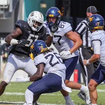 Oct 28, 2023; Orlando, Florida, USA; West Virginia Mountaineers running back Justin Johnson Jr. (26) is tackled by UCF Knights defensive end Malachi Lawrence (51) during the second half at FBC Mortgage Stadium. Mandatory Credit: Mike Watters-Imagn Images
