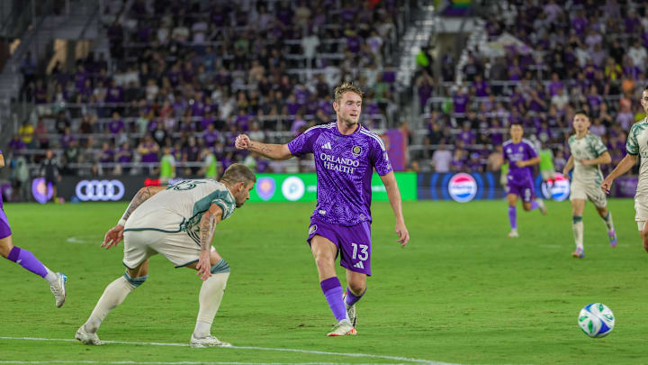 May 24, 2025; Orlando, Florida, USA; Orlando City forward Duncan McGuire (13) kicks the ball against Portland Timbers defender Dario Župaric (13) during the second half at Inter&Co Stadium. Mandatory Credit: Mike Watters-Imagn Images