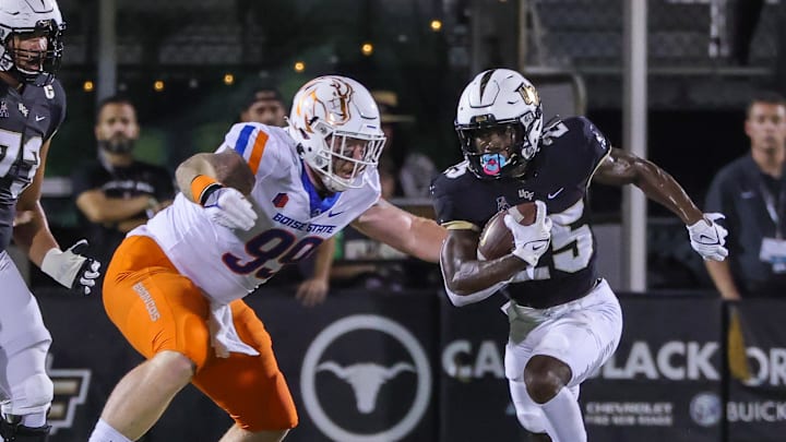 Sep 2, 2021; Orlando, Florida, USA; UCF Knights running back Johnny Richardson (25) runs the ball as Boise State Broncos defensive tackle Scott Matlock (99) moves in during the first quarter at Bounce House. Mandatory Credit: Mike Watters-Imagn Images Sep 2, 2021; Orlando, Florida, USA; UCF Knights running back Johnny Richardson (25) runs the ball as Boise State Broncos defensive tackle Scott Matlock (99) moves in during the first quarter at Bounce House. Mandatory Credit: Mike Watters-Imagn Images