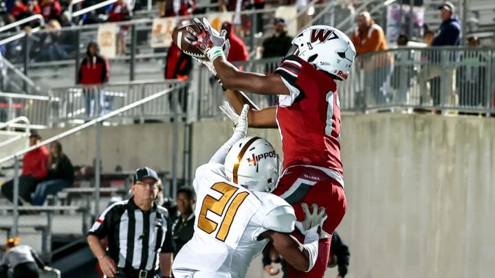 Weiss freshman Tre Moore leaps over Hutto's Braylon Beckworth (21) in a district finale in Pflugerville on Nov. 2, 2023. 