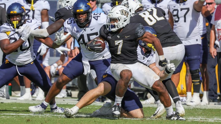 Oct 28, 2023; Orlando, Florida, USA; UCF Knights running back RJ Harvey (7) carries the ball as West Virginia Mountaineers defensive lineman Taurus Simmons (45) moves in during the second half at FBC Mortgage Stadium. Mandatory Credit: Mike Watters-USA TODAY Sports