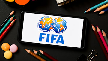 In this photo illustration a FIFA logo seen displayed on a...