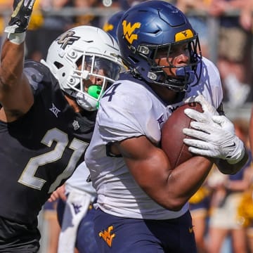 Oct 28, 2023; Orlando, Florida, USA; West Virginia Mountaineers running back CJ Donaldson Jr. (4) carries the ball as UCF Knights defensive back Nikai Martinez (21) move in for the tackle during the second half at FBC Mortgage Stadium. Mandatory Credit: Mike Watters-USA TODAY Sports