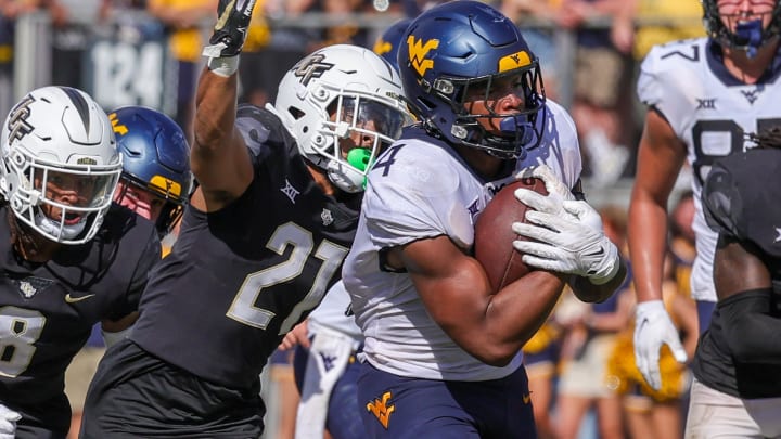 Oct 28, 2023; Orlando, Florida, USA; West Virginia Mountaineers running back CJ Donaldson Jr. (4) carries the ball as UCF Knights defensive back Nikai Martinez (21) move in for the tackle during the second half at FBC Mortgage Stadium. Mandatory Credit: Mike Watters-USA TODAY Sports