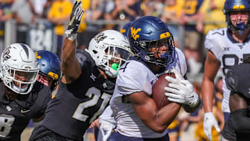 Oct 28, 2023; Orlando, Florida, USA; West Virginia Mountaineers running back CJ Donaldson Jr. (4) carries the ball as UCF Knights defensive back Nikai Martinez (21) move in for the tackle during the second half at FBC Mortgage Stadium. Mandatory Credit: Mike Watters-Imagn Images