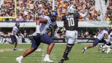 Oct 28, 2023; Orlando, Florida, USA; UCF Knights quarterback John Rhys Plumlee (10) passes the ball as West Virginia Mountaineers defensive lineman Sean Martin (91) moves in during the second quarter at FBC Mortgage Stadium. Mandatory Credit: Mike Watters-USA TODAY Sports