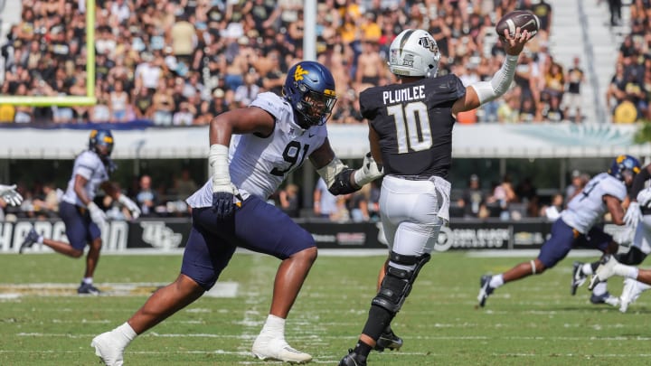 Oct 28, 2023; Orlando, Florida, USA; UCF Knights quarterback John Rhys Plumlee (10) passes the ball as West Virginia Mountaineers defensive lineman Sean Martin (91) moves in during the second quarter at FBC Mortgage Stadium. Mandatory Credit: Mike Watters-USA TODAY Sports