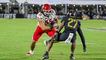 Nov 29, 2024; Orlando, Florida, USA; UCF Knights offensive lineman Cameron Kinnie (55) carries the ball against UCF Knights defensive back Chasen Johnson (27) during the second quarter at FBC Mortgage Stadium. Mandatory Credit: Mike Watters-Imagn Images