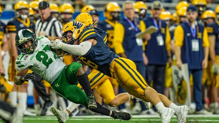 Hudsonville’s Connor Brintnall tackles Detroit Cass Tech RB Jaylen Spates during the 2024 MHSAA Division 1 football finals. Hudsonville hosts Byron Center Thursday night to kick off the 2025 Michigan high school football season. 