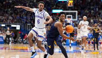 Dec 31, 2024; Lawrence, Kansas, USA; West Virginia Mountaineers guard Joseph Yesufu (1) drives against Kansas Jayhawks guard Rylan Griffen (6) during the first half at Allen Fieldhouse. Mandatory Credit: Jay Biggerstaff-Imagn Images