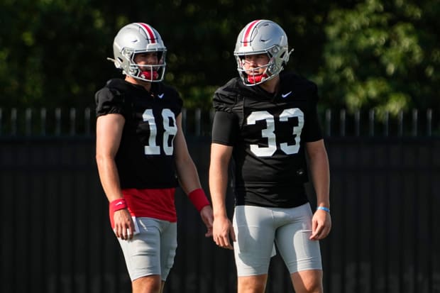 Quarterbacks stand next to each other during practice.